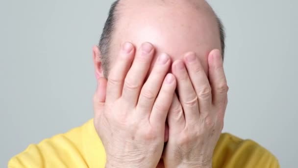 Close up of a stressed elder man closing his face with hands. — Stock Video