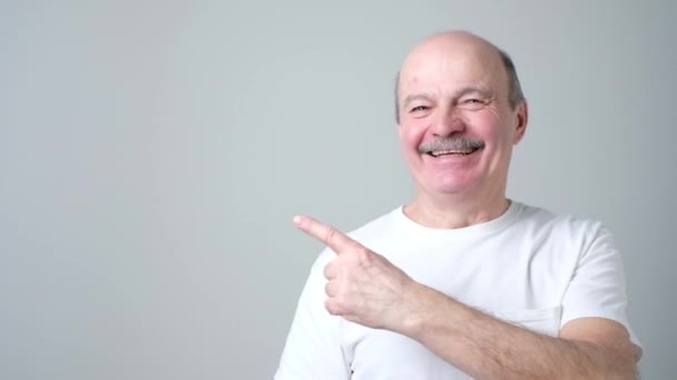 Senior im weißen T-Shirt zeigt mit Zeigefinger auf wichtige Informationen — Stockvideo