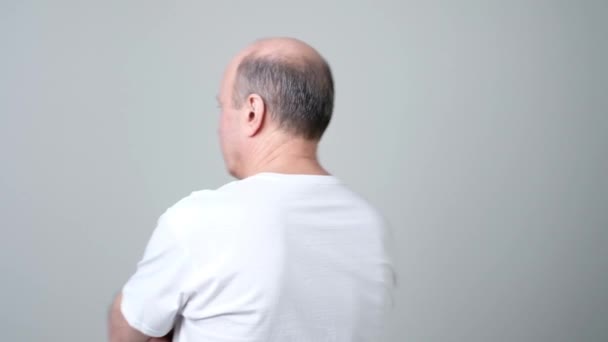 Senior man stands with his back to the camera and turns looking irritated — Stock Video