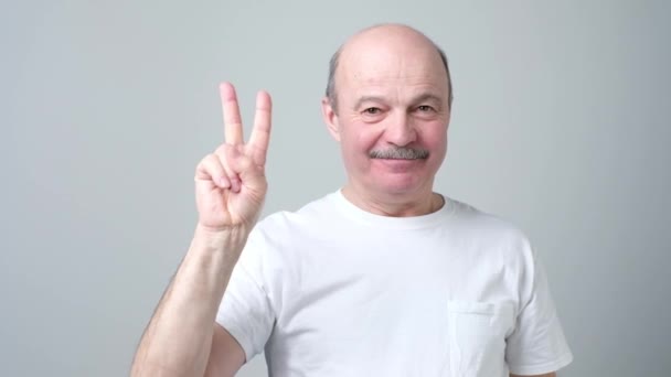 Senior man verhogen twee vingers omhoog op hand vrede of overwinning symbool tonen. — Stockvideo