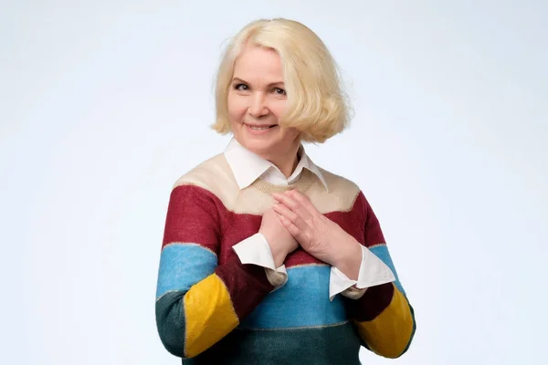 Mujer bastante mayor vistiendo suéter de color se toca con cumplido — Foto de Stock