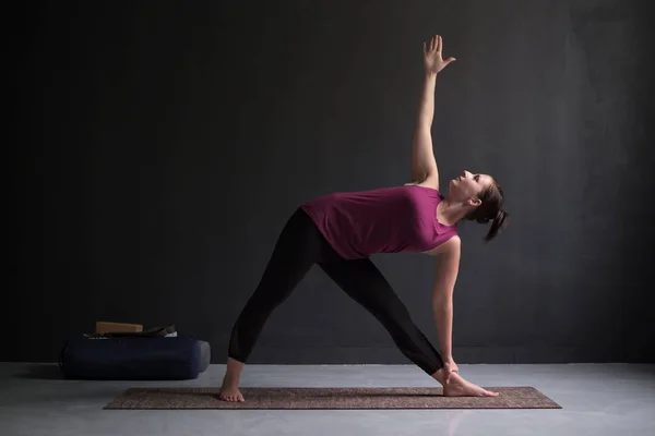 Meisje permanent in Utthita Trikonasana, extended triangle pose. — Stockfoto