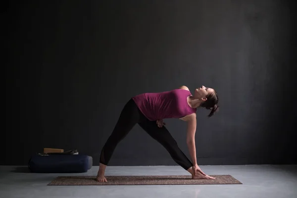 Meisje permanent in Utthita Trikonasana, extended triangle pose. — Stockfoto