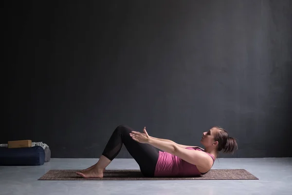 Ung kvinna öva yoga asana Ardha Navasana motion på yogastudio — Stockfoto