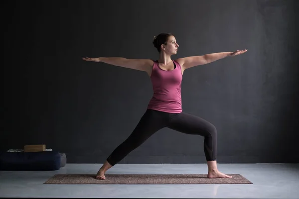 Kvinna utövar yoga, stående i Warrior två övningen Virabhadrasana Ii pose — Stockfoto