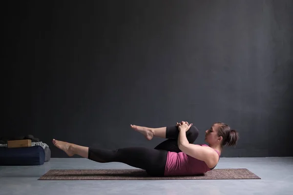 Mujer haciendo Hatha Yoga asana Ardha pawanmuktasana o rodillas para posar en el pecho . — Foto de Stock