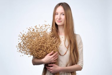 Keten lon saçlı güzel bir kızın elinde çiçek kurutulmuş.