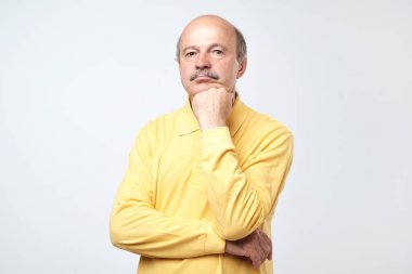 Düşünme ve şaşkın bakıyor Sarı tişörtlü rahat olgun adam portresi.
