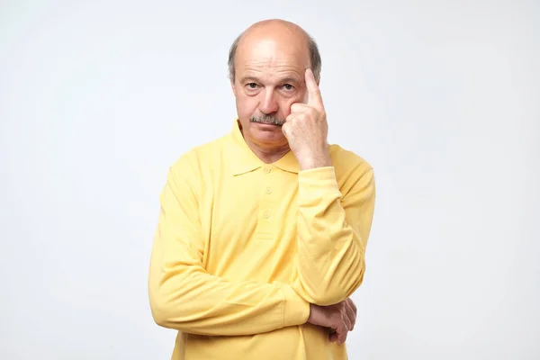 Портрет взрослого мужчины в желтой рубашке, думающего и выглядящего озадаченным . — стоковое фото