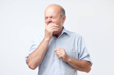 Kel emekli adam uykulu geliyor, yorgun hissediyor gibi kükrüyor, yaygın olarak ağız açılır,
