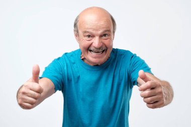 Üst düzey kel adam neşeli ellerini havaya atar.