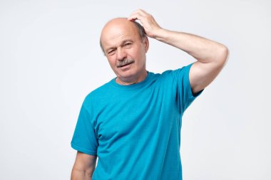 Düşünme ve şaşkın bakıyor mavi tişörtlü rahat olgun adam portresi.