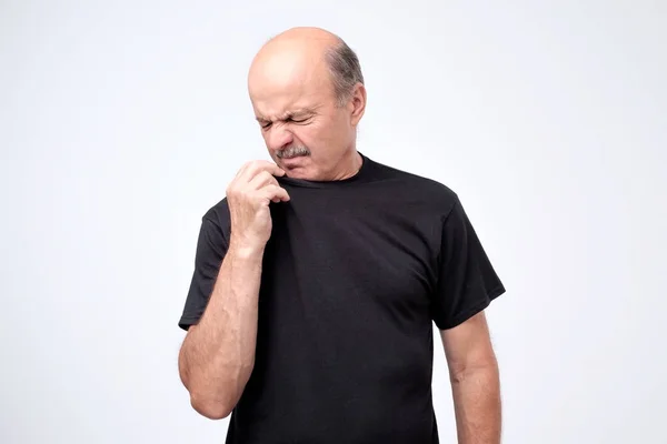 Reifer Mann mit Glatze im schwarzen T-Shirt, der etwas Unangenehmes und Schlechtes riecht — Stockfoto