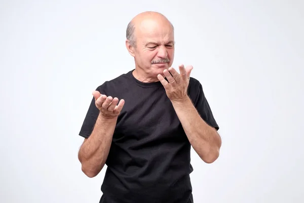 Лысый взрослый мужчина в черной футболке пахнет чем-то неприятным и плохим — стоковое фото