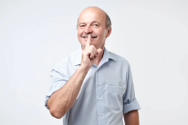 Reifer Mann mit dem Finger auf den Lippen bittet um Schweigen. — Stockfoto