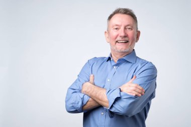 Kameraya bakarak ve gülümseyen rahat kıyafetli emin yakışıklı olgun adam