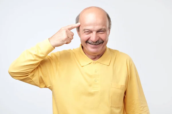 Homem sênior sorrindo apontando para a cabeça com um dedo, grande ideia ou pensamento — Fotografia de Stock