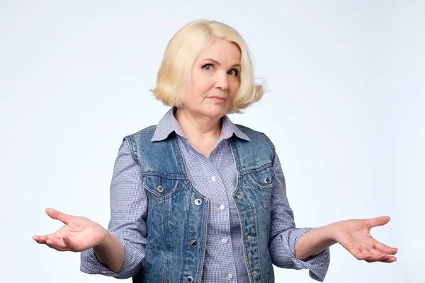 Retrato de una mujer mayor agradable que tiene un gesto de duda . — Foto de Stock