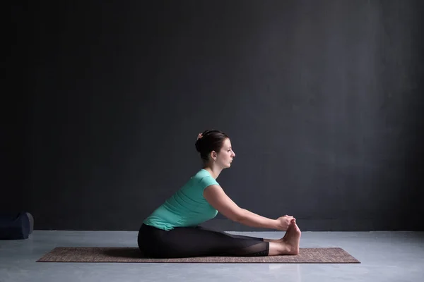 Mujer practicando yoga, pose inclinada hacia adelante sentada — Foto de Stock