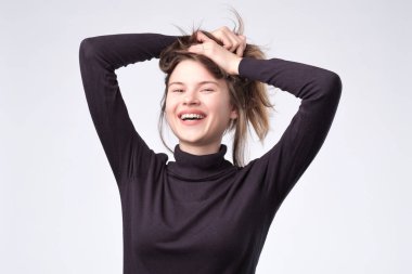 Uzun saçlı kadın beyaz duvardan gülüyor.