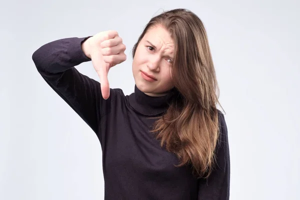 Mooie jonge vrouw thumbing omlaag, geïsoleerde op witte achtergrond. — Stockfoto