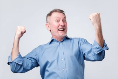 Yaşasın harekete, sıkışık yumruk yükselterek mutlu üst düzey güçlü adam, zafer