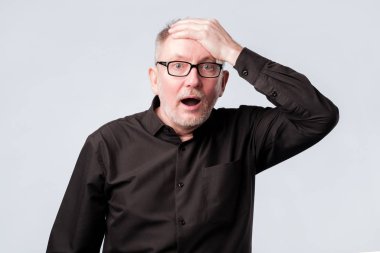 Senior man in black shirt putting his hand on the forehead remembering something clipart
