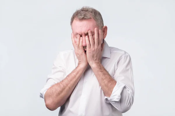 Senior im weißen Hemd verdeckt sein Gesicht mit beiden Händen — Stockfoto