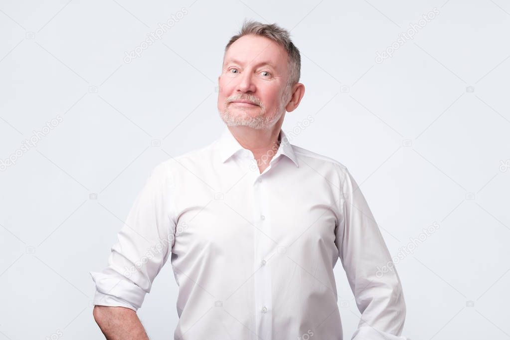 Smiling senior man in white shirt standing and smiling at camera feeling good