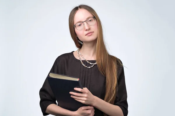 Studentka v brýlích s dlouhými vlasy drží knihu preapring na zkoušku. — Stock fotografie