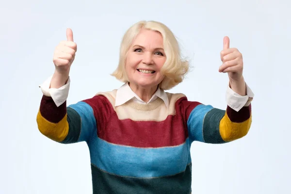 Alegre anciana en suéter de color mostrando los pulgares hacia arriba gesto — Foto de Stock