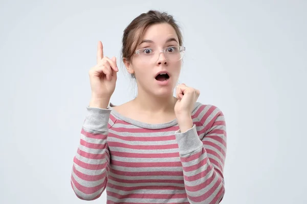 Mädchen in gestreifter Kleidung zeigt Zeigefinger nach oben und gibt Ratschläge — Stockfoto