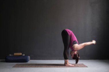 Sportif kadın pratik yoga, ileriye doğru viraj egzersiz, uttanasana poz ayakta.