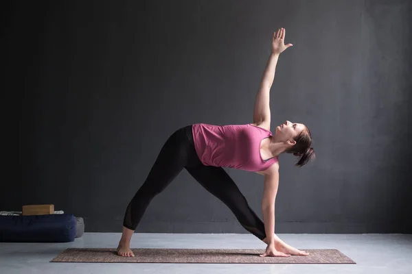 Menina em pé em Utthita Trikonasana, pose triangular estendida . — Fotografia de Stock