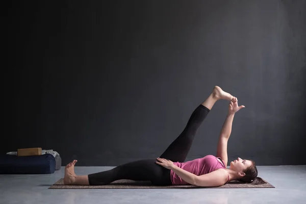Kvinnan gör Yoga asana Supta padangusthasana eller liggande hand till stortån pose — Stockfoto