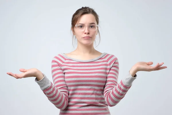 Puzzled young woman dressed casually shrugs shoulders as does not know answer — Stock Photo, Image