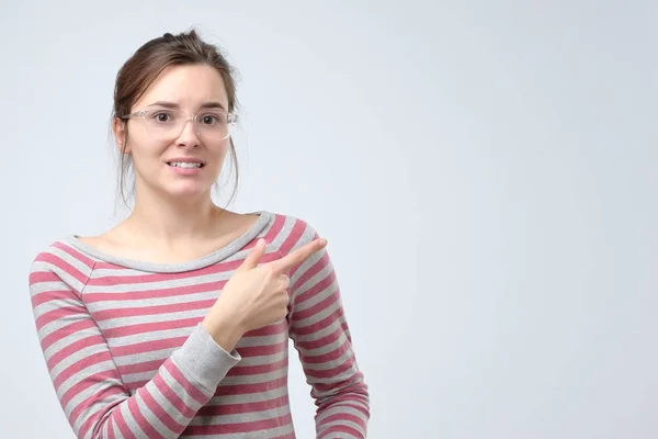 Молодая европейская женщина, указывающая на копирайт, показывает пальцем вверх — стоковое фото