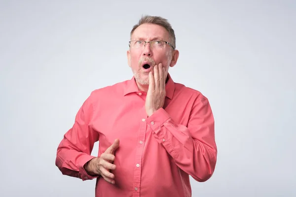 Senior man in een rood shirt tand pijn lijden. — Stockfoto