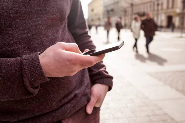 Человек со смартфоном на городской улице, проверяет электронную почту — стоковое фото