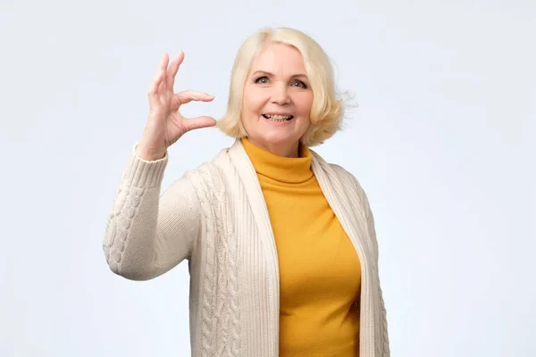 Mujer mayor mostrando el signo de tamaño pequeño con los dedos — Foto de Stock