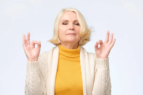 Mujer mayor haciendo gesto de meditación con los dedos — Foto de Stock