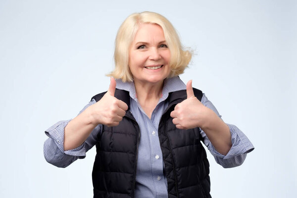 happy blonde senior woman showing thumbs up
