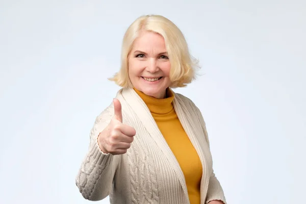 Щаслива блондинка старша жінка показує великі пальці вгору — стокове фото