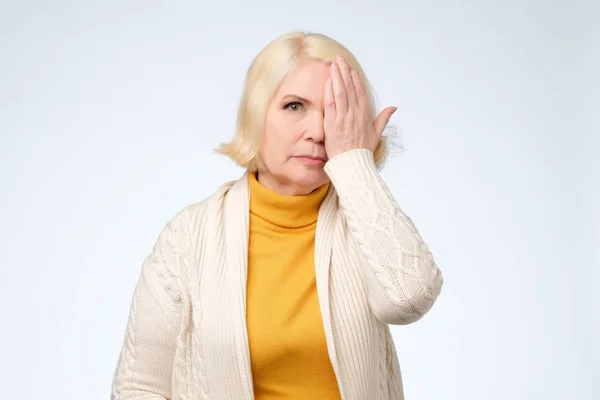 Mujer mayor cubriendo un ojo con su mano — Foto de Stock