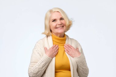 Pretty senior blonde woman is touched with compliment clipart