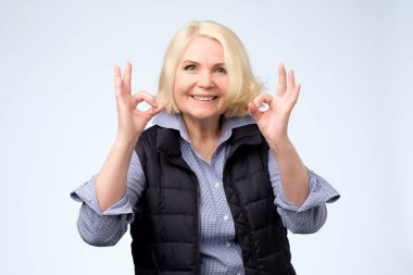 Gülümseyen kıdemli sarışın Bayan ok işareti işaret