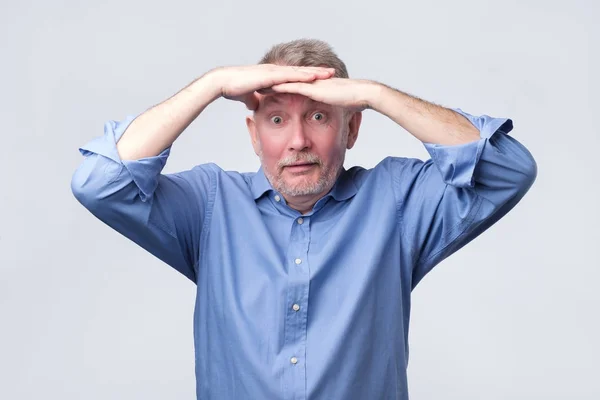 Senior man in blauw shirt Kijk ver weg. — Stockfoto