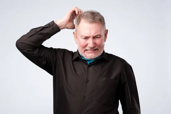 Porträt eines lässigen reifen Mannes in schwarzem Hemd, der nachdenkt und verwirrt wirkt. — Stockfoto