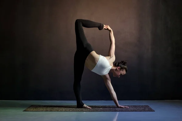 Jonge Kaukasische slanke yoga meisje doet variatie van Adho Mukha shvanasana. — Stockfoto