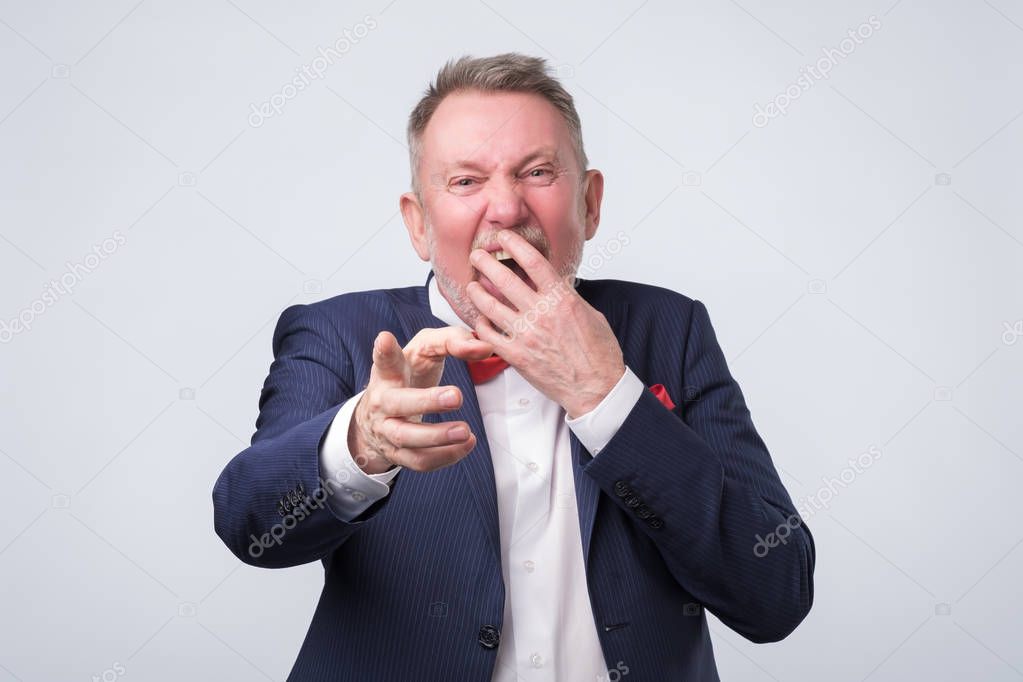 Senior man laughs at you, teasing, pointing with finger.